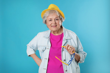 Wall Mural - Portrait of mature woman in hipster outfit on color background