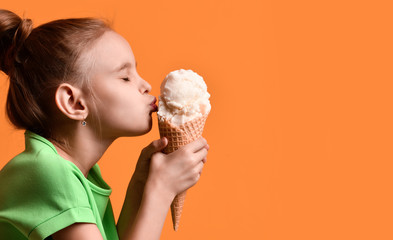 little baby girl kid kissing vanilla ice cream in waffles cone on yellow orange background in green 