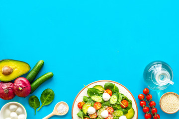 Wall Mural - Cooking fresh salad. Vegetables, greens, spices, plate of salad on blue kitchen desk top view space for text