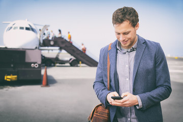 Wall Mural - man texting on phone leaving for business trip at airport . happy businessman on smartphone boarding