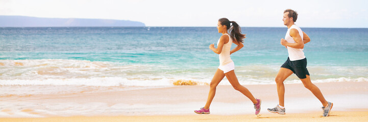 Wall Mural - Run fit couple running together on beach banner panoramic background. Two fitness athlete jogging - summer active lifestyle.