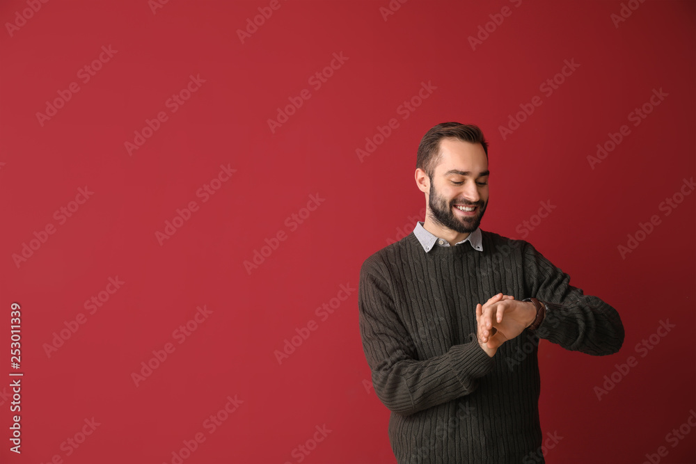 Young businessman looking on his watch against color background