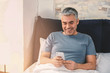 © Pixel-Shot - Mature man with mobile phone in bed
