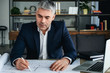 © Pixel-Shot - Mature architect working with drawings in office