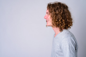 Wall Mural - Closeup profile view of happy young handsome man with curly hair smiling