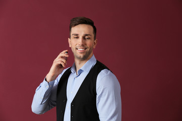 Wall Mural - Handsome man with bottle of perfume on color background