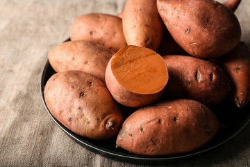 Plate with raw sweet potato on table, closeup