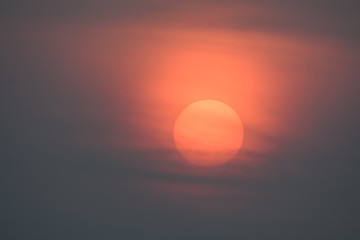 The big red sun is slowly falling, with large black clouds in front.