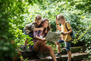 Wall Mural - mother and her little sons hiking .they taking a break and sitting on the old stairs.examining map.