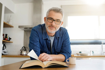 Wall Mural - Man reading book at home in modern kitchen