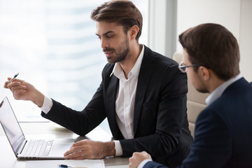 Canvas Print - Serious businessman manager talking with client pointing at laptop