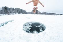Young Man Jumps And Flies Into The Ice Hole Made On The Winter Lake