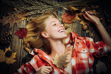 Wall Mural - Autumn concept. Attractive woman wearing in fashionable seasonal clothes having Autumnal mood. Autumn discounts. Sweet young woman playing with leaves, looks very sensually.