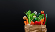 Fresh Organic Vegetables In Brown Paper Bag Against Dark Table Background