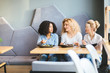© Iryna - Three multi ethnic  girlfriends talking, sitting in a row gathering to drink smoothies and eating salad enjoying tasty healthy food at cozy cafe. Multi-racial, difference cultures friendship concept.