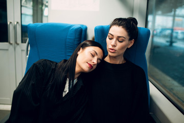 Two girlfriends sleeping during trip by railway train