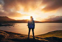 Man Standing In Blue Jacket Looking At Spectacular Sunset Over Frostadavatn Lake In Landmannalaugar In Iceland