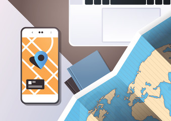 Poster - navigation online application paper world map with gps location mark top angle view workplace desktop with cell smartphone laptop office stuff horizontal