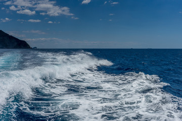 Italy, Cinque Terre, Monterosso, a man riding a wave on top of a body of water