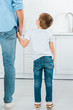 © LIGHTFIELD STUDIOS - back view of preschooler holding hands with father at home