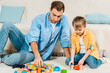 © LIGHTFIELD STUDIOS - father and preschooler son playing with colorful building blocks and toy cars at home
