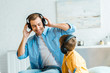 © LIGHTFIELD STUDIOS - handsome smiling father with preschooler son in headphones listening music at home