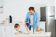 © LIGHTFIELD STUDIOS - handsome father pouring cereal in bowl while preschooler son drawing during breakfast in morning