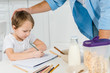 © LIGHTFIELD STUDIOS - father stroking preschooler son drawing during breakfast in kitchen
