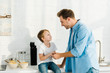 © LIGHTFIELD STUDIOS - father and preschooler son with bowls on cereal on counter during breakfast in kitchen