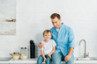 © LIGHTFIELD STUDIOS - happy father and preschooler son with bowls on cereal on counter during breakfast in kitchen