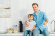 © LIGHTFIELD STUDIOS - father and preschooler son looking at camera and showing thumbs up signs during breakfast in kitchen
