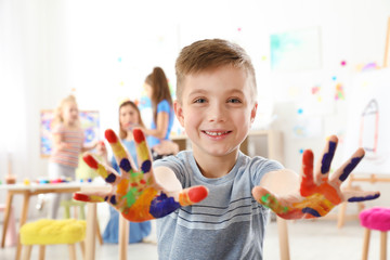 Sticker - Cute little child showing painted hands at lesson indoors