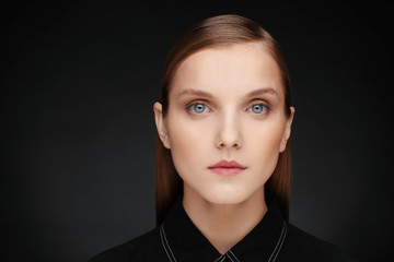 Close-up portrait of a beautiful model with clean makeup and collected hair, photographed in a photo studio