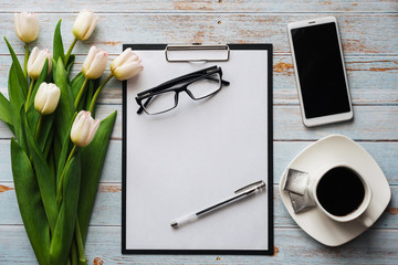 Wall Mural - White bouquet of tulips on wooden background with coffee Cup, smartphone and empty notebook
