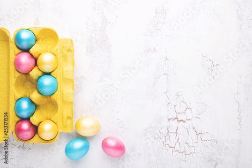 Colorful Easter eggs in egg tray on white craquelure table. Holiday backgroun...