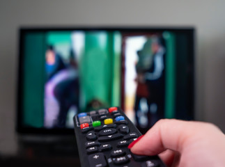 female hand with remote control on the background of the TV