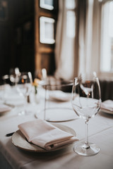 Wall Mural - A close up shot of a restaurant table set up with tableware and wine glass. Concept of dining, hospitality and catering. Vertical image with free space for text.