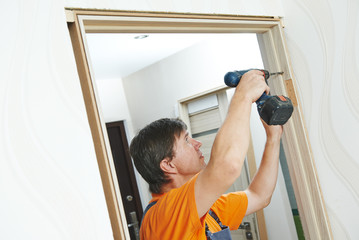 Wall Mural - Door frame installation. Carpenter works with drill