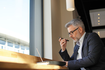 Wall Mural - Businessman talking on cellphone prepping meeting in airport