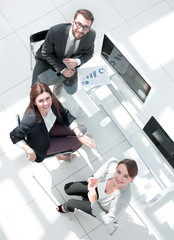 Poster - top view.business colleagues sitting at the Desk and looking at the camera