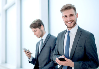 Wall Mural - successful employees using their smartphones sitting in the office lobby