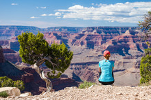 Young Woman Sitting On The Edge Of Grand Canyon Enjoying The View. Grand Canyon Hiker Woman Resting. Hiking Caucasian Girl Relaxing On  South Rim Of Grand Canyon, Arizona