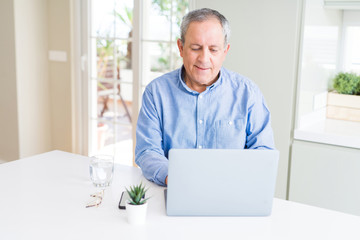 Wall Mural - Handsome senior man using laptop and smiling