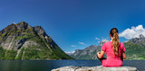 Fototapeta  - Frau sitzt an einem Fjord