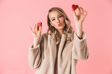 Canvas Print - Beautiful happy young pretty woman posing isolated over pink wall background holding hearts.