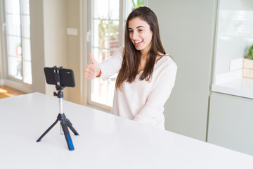 Poster - Beautiful young woman recording selfie video with smartphone webcam happy with big smile doing ok sign, thumb up with fingers, excellent sign