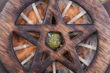 Wooden encircled Pentagram symbol with Unakite stone in the middle of a circle made of colorful parrot feathers. Five elements: Earth, Water, Air, Fire, Spirit. 