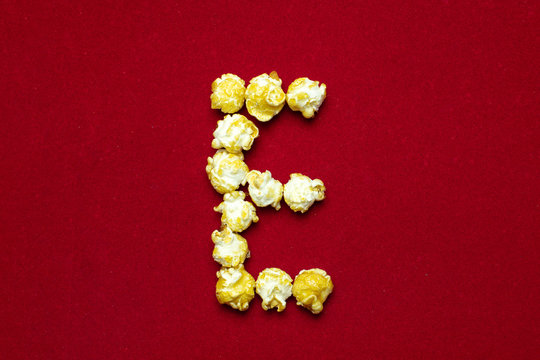 English alphabet from cinema popcorn. Letter E. Red background for design. Movie styling.