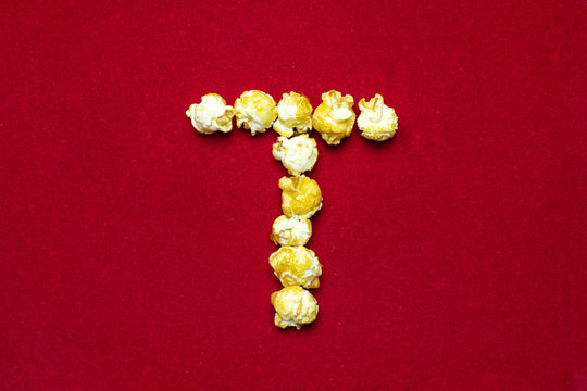 English alphabet from cinema popcorn. Letter T. Red background for design. Movie styling.