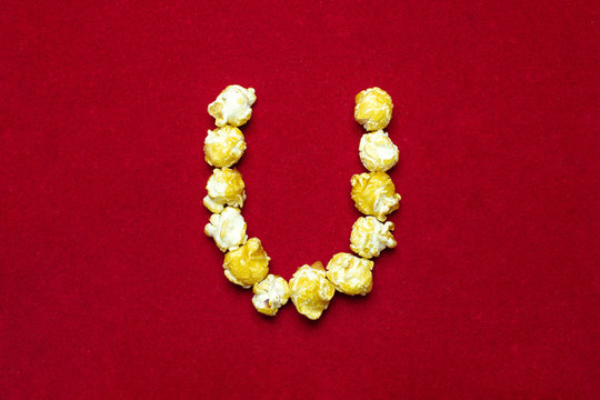English alphabet from cinema popcorn. Letter U. Red background for design. Movie styling.